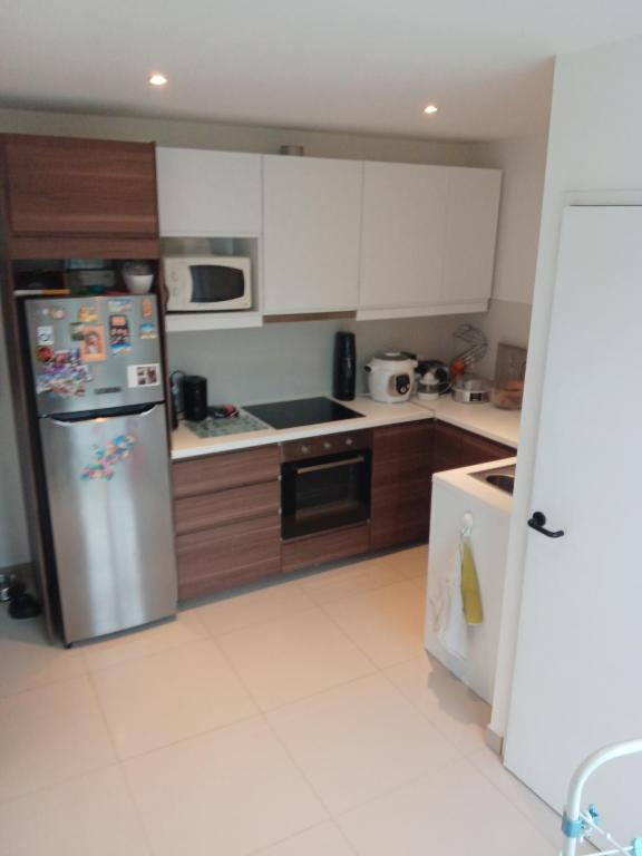 eine Küche mit weißen Schränken und einem Edelstahlkühlschrank in der Unterkunft Belle maison avec 3 chambres et jardin in Itteville