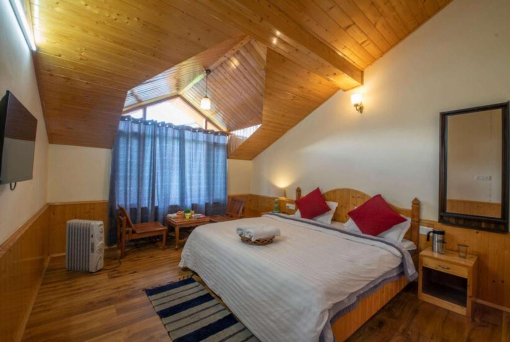 a bedroom with a large bed with red pillows at Goroomgo Urban Monk Stays, Manali in Manāli