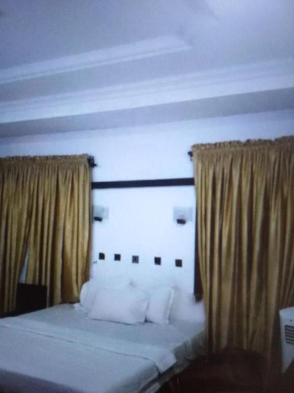 1 cama con almohadas blancas y cortinas en una habitación en N.V HOTEL AND RESORT BEACH view en Lagos