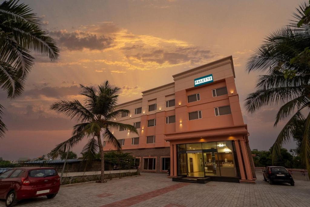 un hotel con coches aparcados delante en Palette - Coastal Grand Hotels & Resorts, OMR, en Chennai