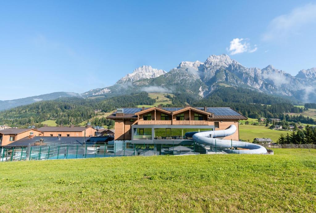 a building with a slide in front of a mountain at Hotel Riederalm in Leogang