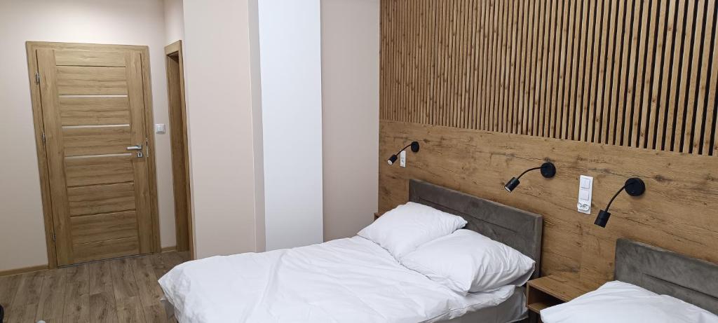 een slaapkamer met 2 bedden en een houten muur bij Ground Floor Rooms in Łomża