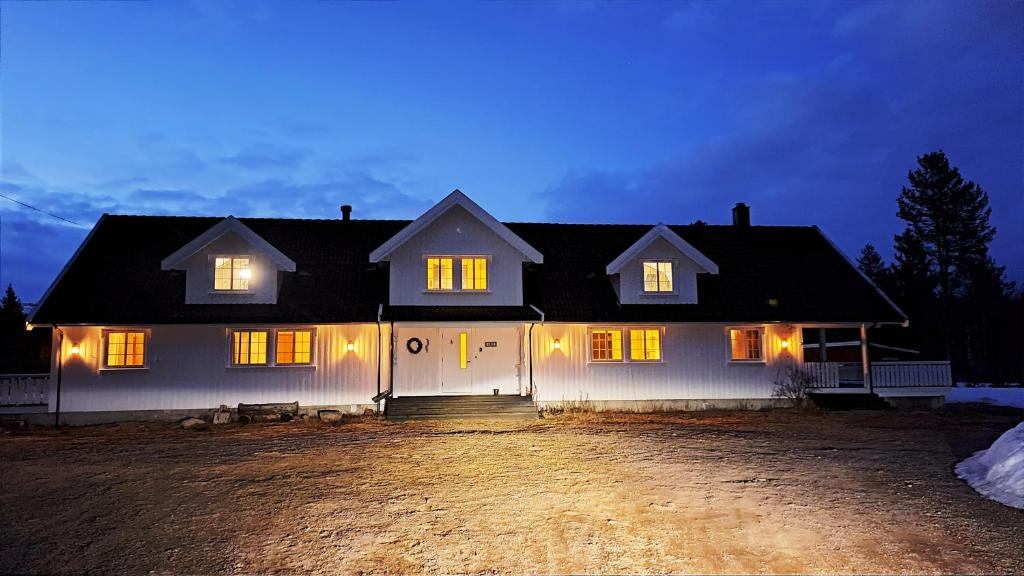Une grande maison blanche éclairée la nuit dans l'établissement Ljøra Lodge - Home of nature and peace - All year, à Ljørdalen