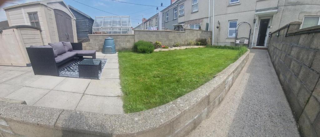 a backyard with a couch and a grass yard at Cosy 3-Bed House in Kidwelly in Kidwelly