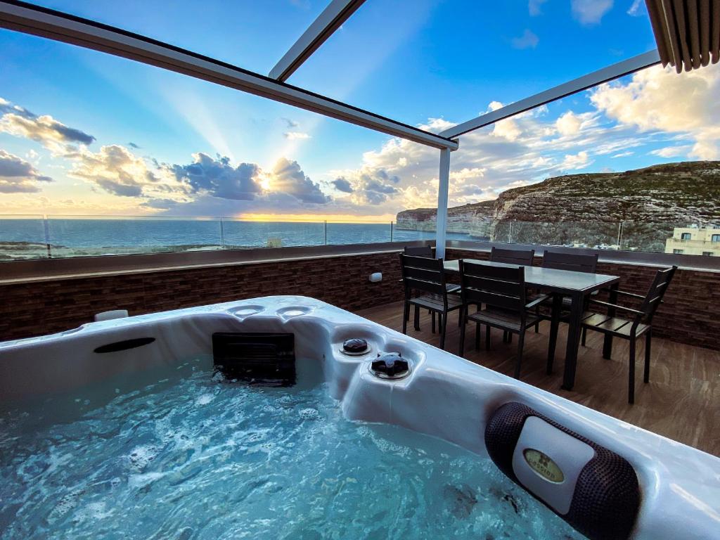 a hot tub in a room with a view of the ocean at Blue Sky Xlendi in Xlendi