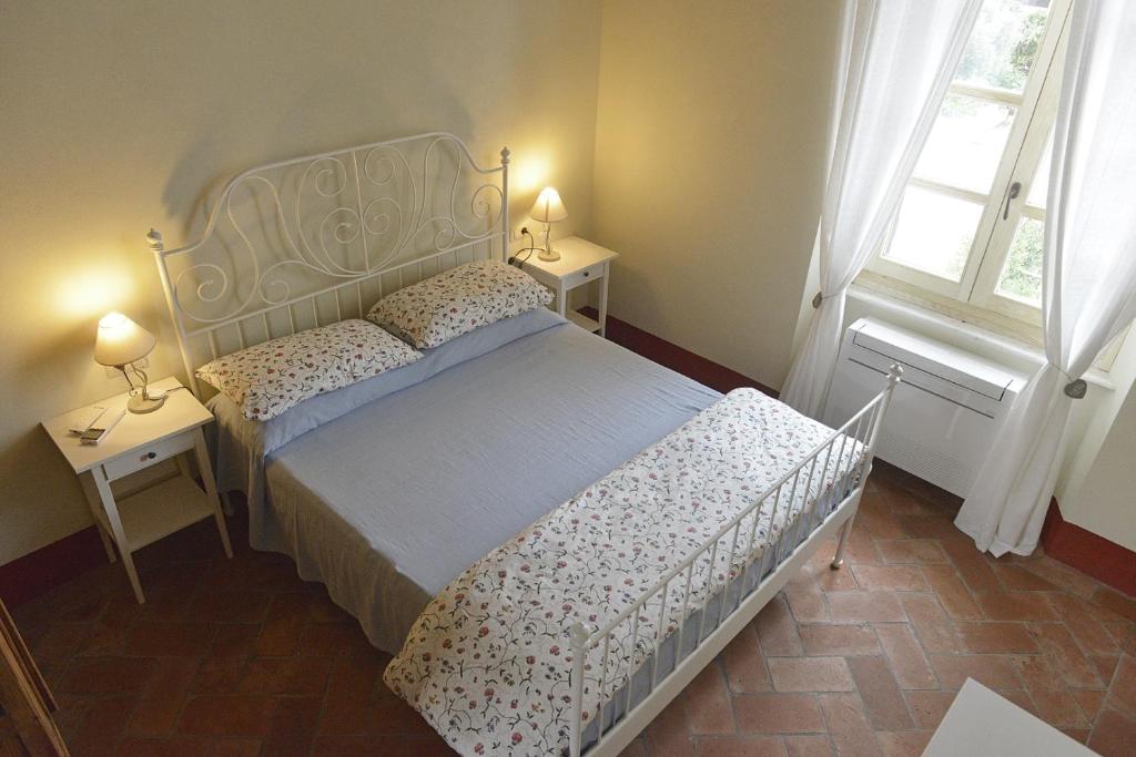 a bedroom with a bed and two tables and two windows at Alloro 5 in Marciana Marina