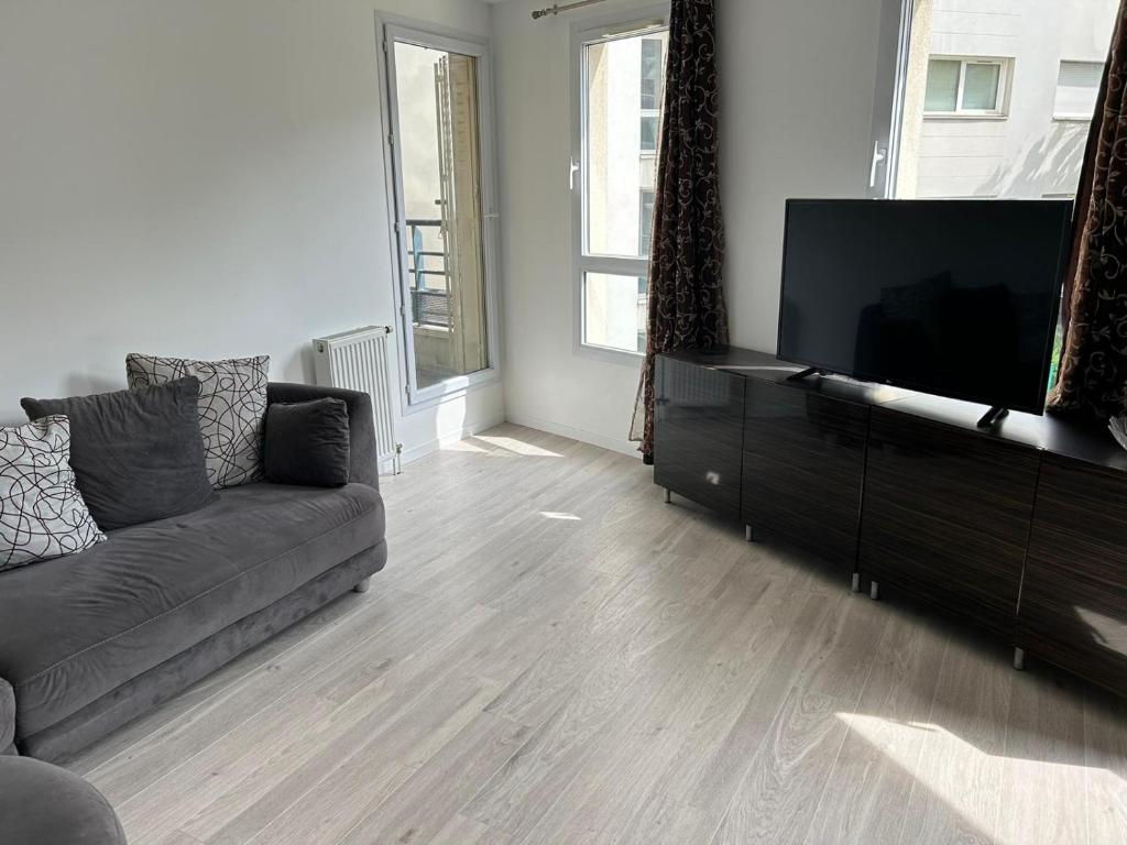 un salon avec un canapé et une télévision à écran plat dans l'établissement Jeux olympiques, à Saint-Denis