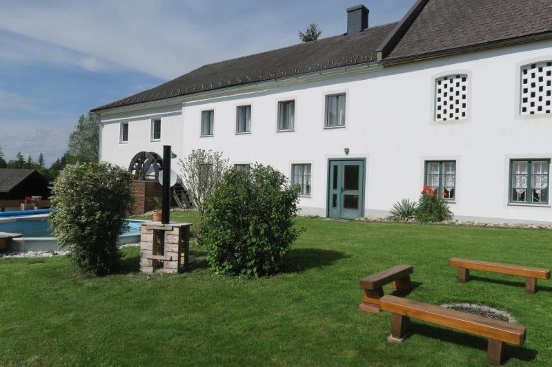 una casa blanca con dos bancos delante en Dörrmühle en Texing