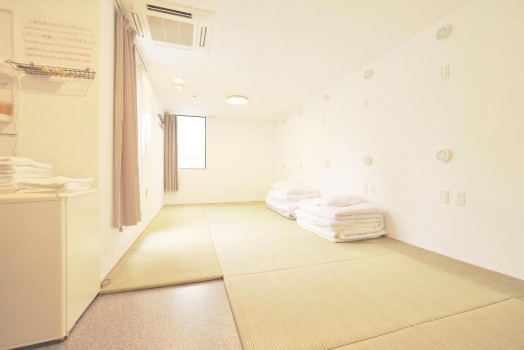 Cette chambre est dotée de murs blancs et de serviettes blanches. dans l'établissement Hananosato Hotel Ikebukuro, à Tokyo