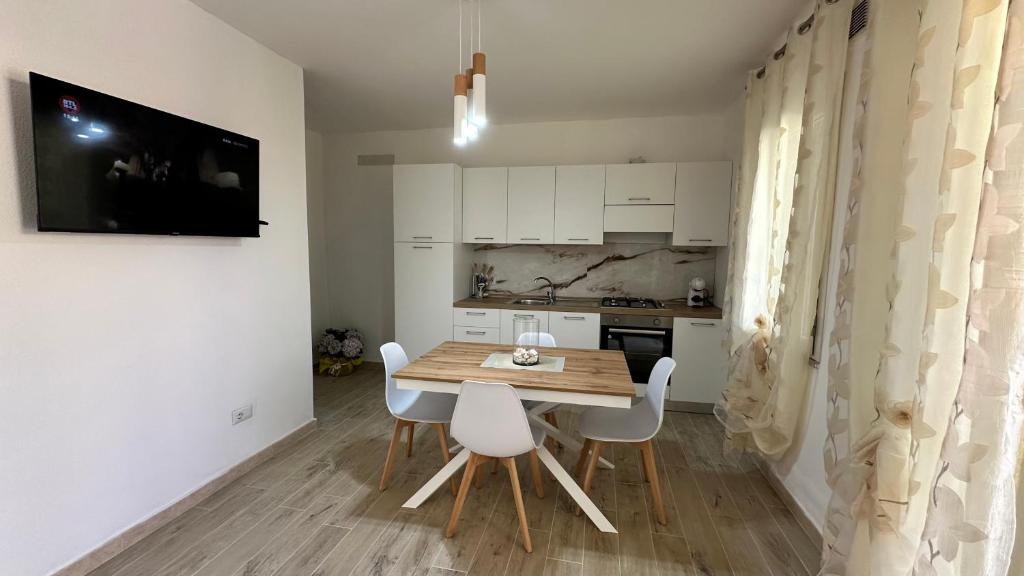 una pequeña cocina con mesa de madera y sillas blancas en Casa Dario, en Tanaunella