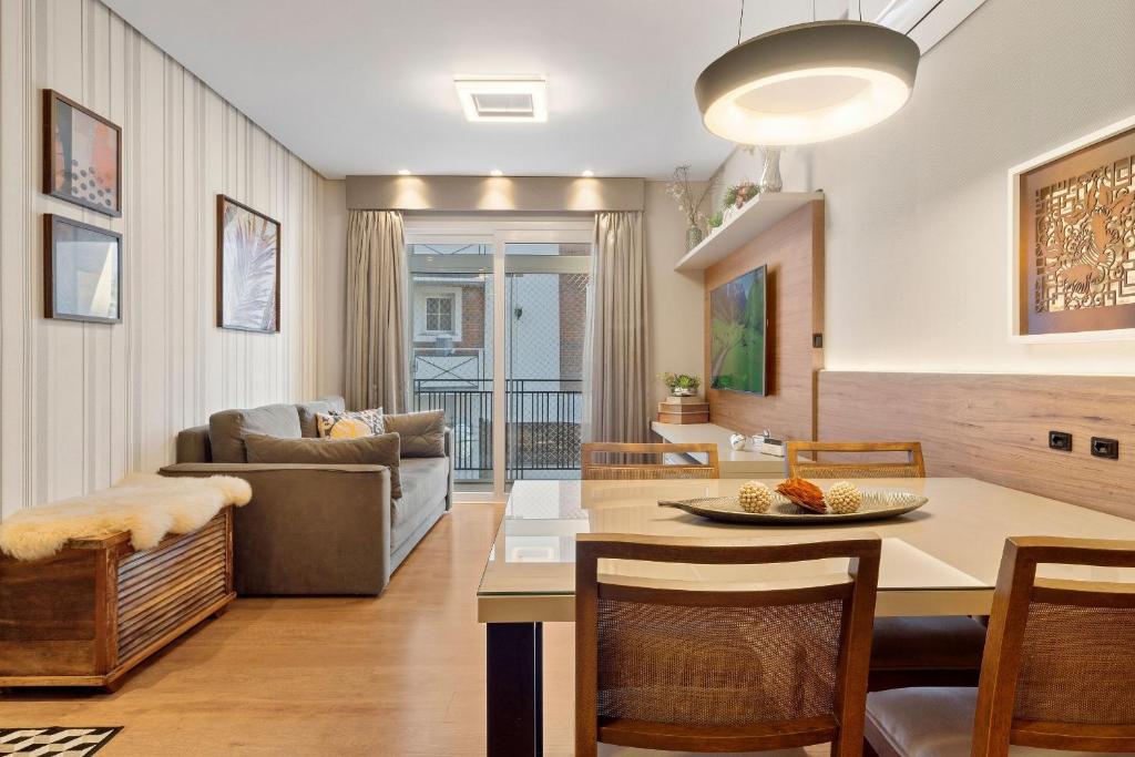 a kitchen and living room with a table and chairs at Apartamento Loft One 1dorm by Achei Gramado in Gramado