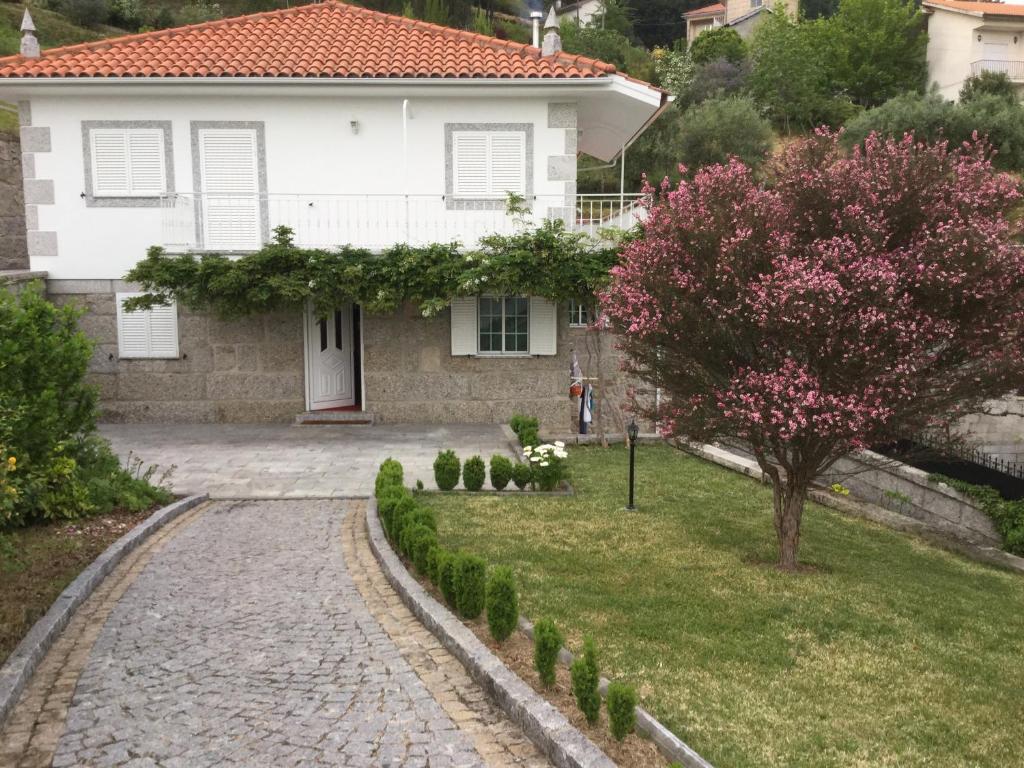 una casa blanca con un árbol y una entrada en Casa dos Encantos, en Arcos de Valdevez
