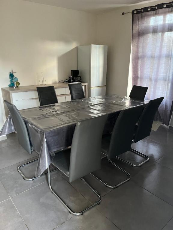 a dining room table with chairs and a table and a kitchen at la maison de laligier in Jaujac