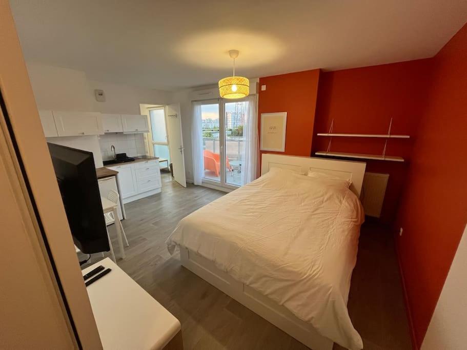 une chambre avec un lit et un bureau avec une télévision dans l'établissement Le Qwartz - vue stade de France, à Villeneuve-la-Garenne