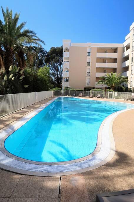 une grande piscine bleue devant un immeuble dans l'établissement Appartement Hyères centre avec piscine et parking privé, à Hyères