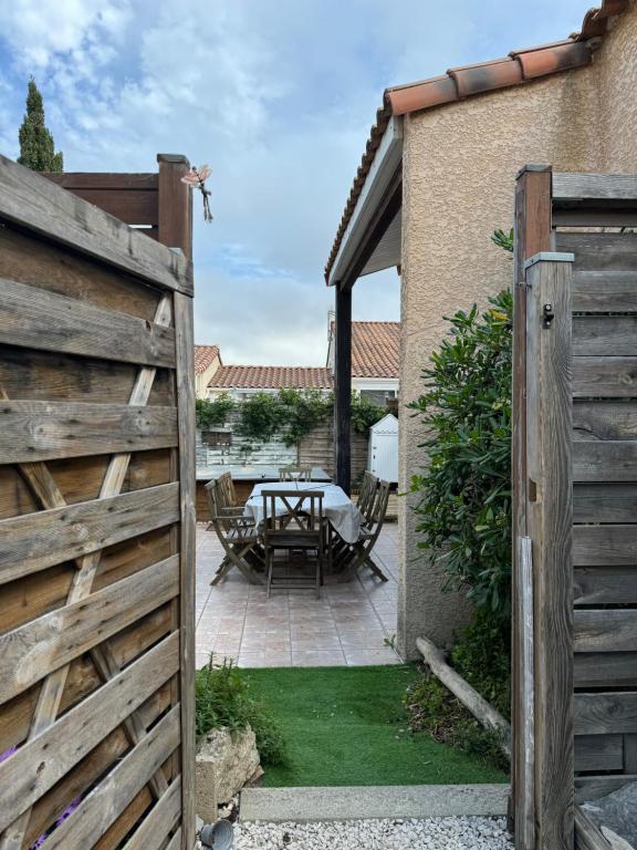 une porte en bois menant à une terrasse avec une table. dans l'établissement La maison bleue de St Pierre, à Saint Pierre La Mer