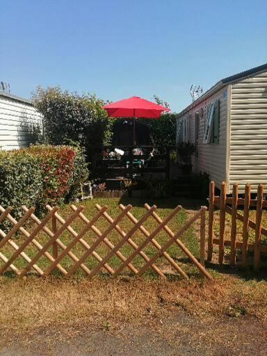 een houten hek in een tuin naast een caravan bij Mobil home centre ville in Pleurtuit