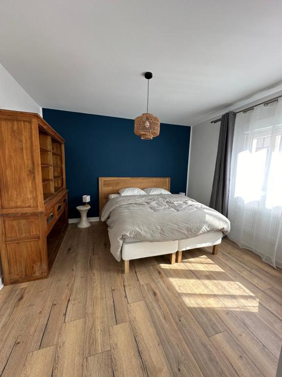une chambre avec un lit et un mur bleu dans l'établissement Bel appartement - LM la Mer, à Berck-sur-Mer