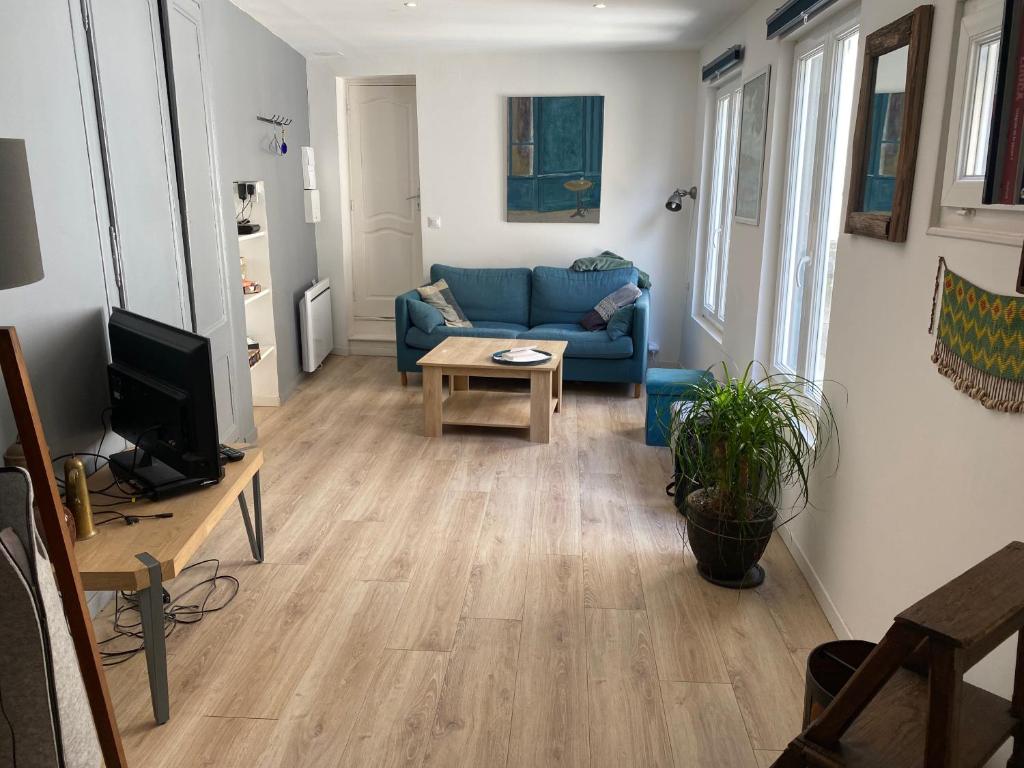 a living room with a blue couch and a tv at MAISONNETTE de charme avec cour privative Haute-Ville GRANVILLE in Granville