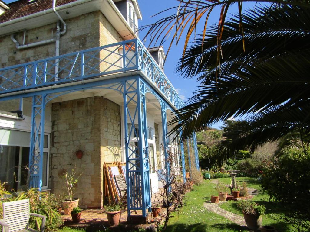 a house with a blue balcony and a palm tree at St Maur in Ventnor