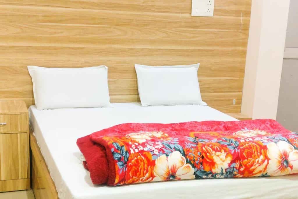 Goroomgo Sangam Palace Guest house Mathura - Prime Location في ماثورا: سرير مع بطانية ملونة عليه وسادتين
