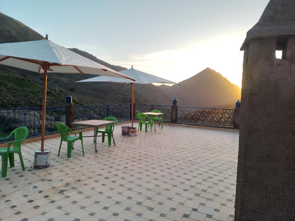 a patio with tables and chairs and an umbrella at Gite Dar Amgdoule in Tacheddirt