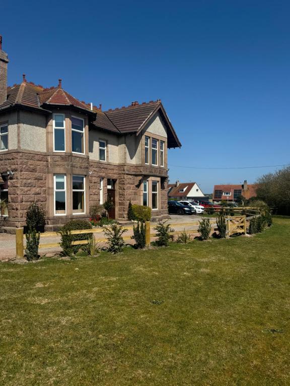 a large brick house with a grass yard at St Olaf Golf Hotel in Cruden Bay