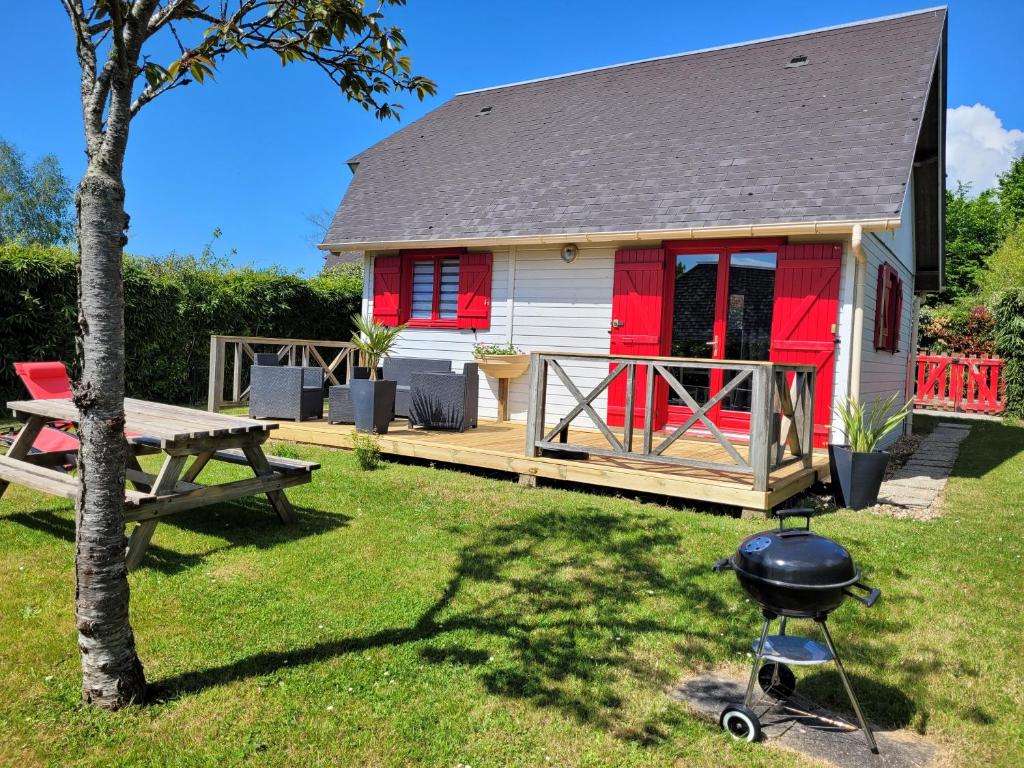 ein Haus mit einem Grill und einem Picknicktisch in der Unterkunft Chalet 31 in Saint-André-dʼHébertot