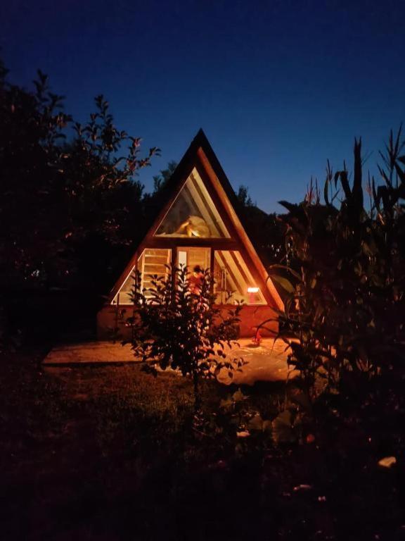 a small house with a window at night at Village Serenity Cottage with outside toilet in Podgorica