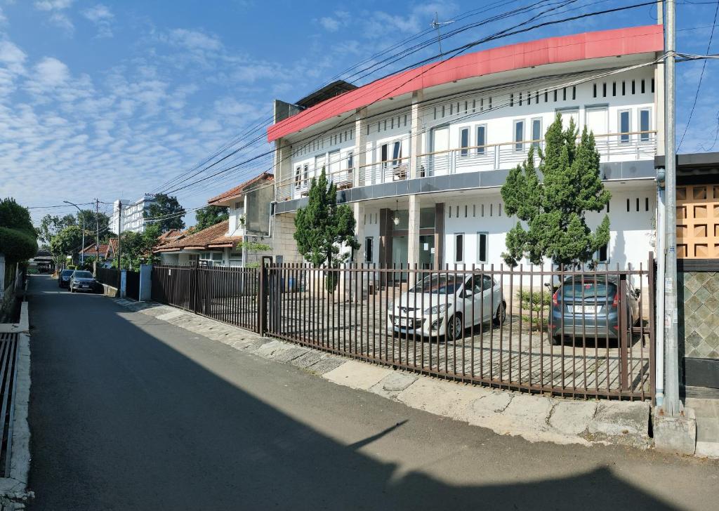 une clôture avec des voitures garées devant un bâtiment dans l'établissement Hotel Residence 5 Syariah, à Bandung
