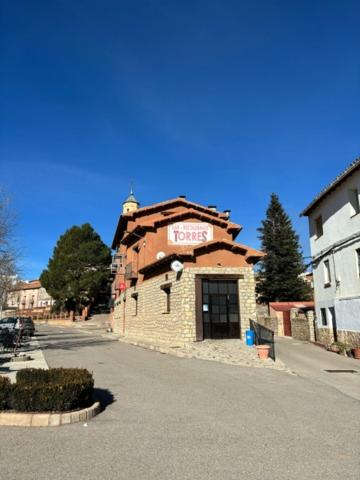 un pequeño edificio de ladrillo con un cartel. en Hotel El Cid, en Torres de Albarracín