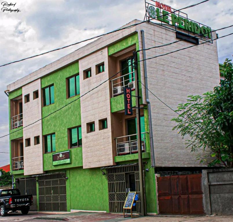 a green and white building with a sign on it at Hôtel LE PÉRIDOT in Brazzaville