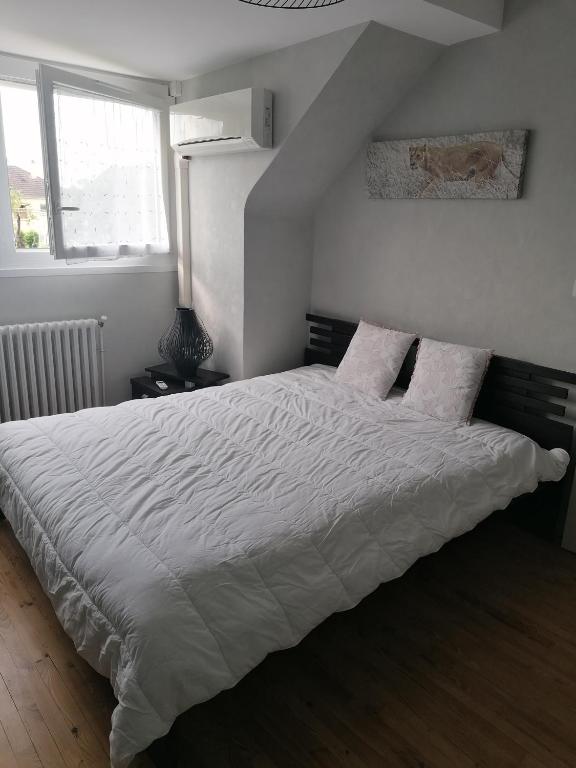 une chambre avec un lit avec des draps blancs et des oreillers dans l'établissement Bougard, à Champagné