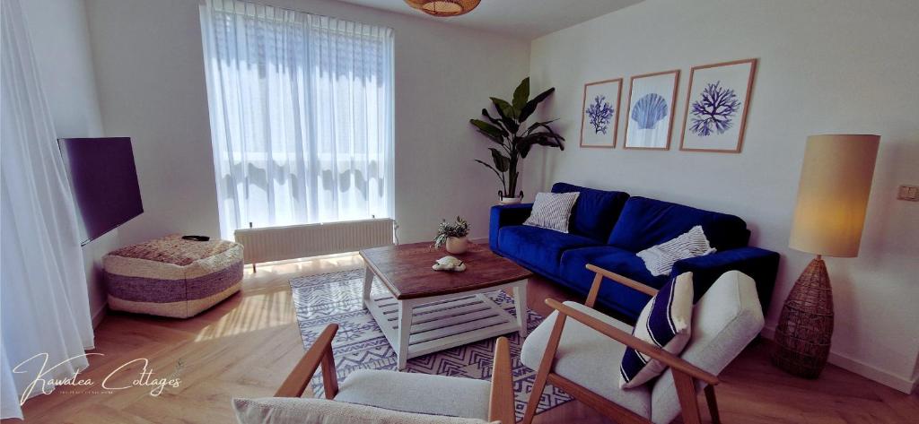 een woonkamer met een blauwe bank en een tafel bij Luxe Wellness cottage met hottub bij Nijmegen in Ewijk