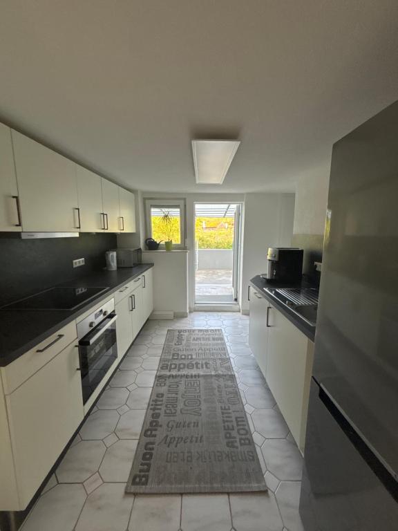 a kitchen with white cabinets and a tile floor at Unterm-Felsen in Bad Überkingen