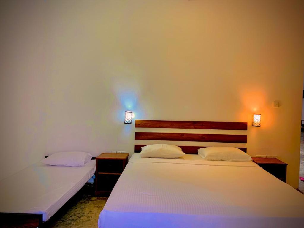 a bedroom with two beds and two lights on the wall at Raddagoda walawwa Hottel in Kurunegala