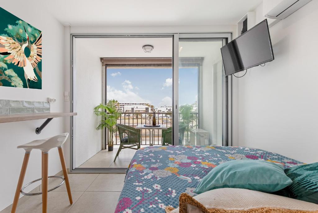 une chambre avec un lit et une vue sur un balcon dans l'établissement Pitaya Heliopolis, au Cap d'Agde