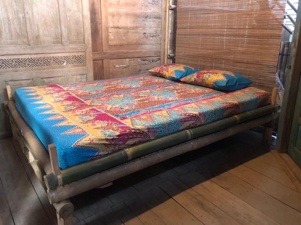 an old bed with a colorful comforter and pillows on it at Omah Guyub 2 in Jarakan