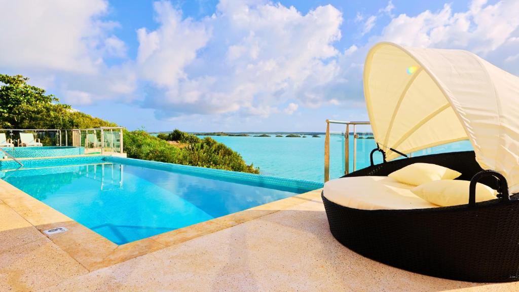 a resort with a swimming pool and a chaise lounge at Alta Bella Villa and Spa in Providenciales