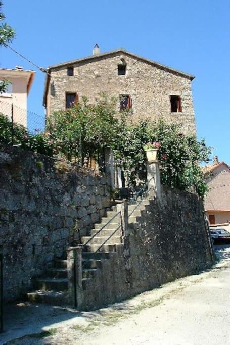 un mur en pierre avec des escaliers menant à un bâtiment dans l'établissement Usupranu Maison de village à 15 mn de la mer, à Sari-dʼOrcino