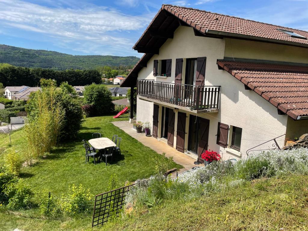 een huis met een balkon en een tafel in de tuin bij Maison entre lacs et fôrets in Montréal La Cluse