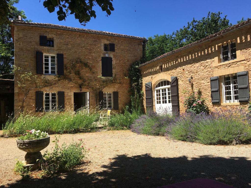 un ancien bâtiment en briques avec un jardin en face de lui dans l'établissement Retour aux sources, à Blanquefort-sur-Briolance