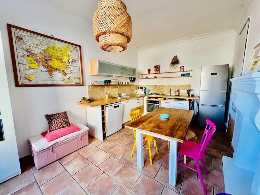 une cuisine avec une table en bois et des chaises roses dans l'établissement Maisonnette au cœur du village, à Châteauvieux