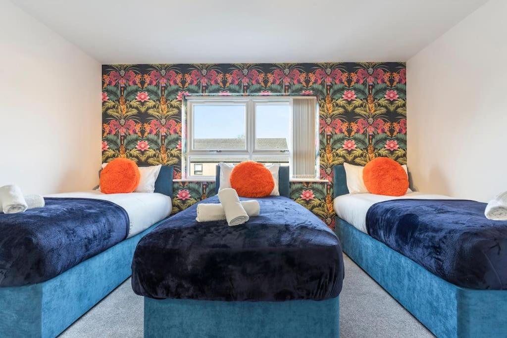 a room with two beds with orange pillows and a window at Luxury City Centre 5 Bed House with FREE parking in Birmingham