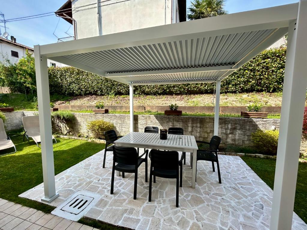 een witte pergola met een tafel en stoelen op een patio bij Il Piccolo Borgo in Valdobbiadene