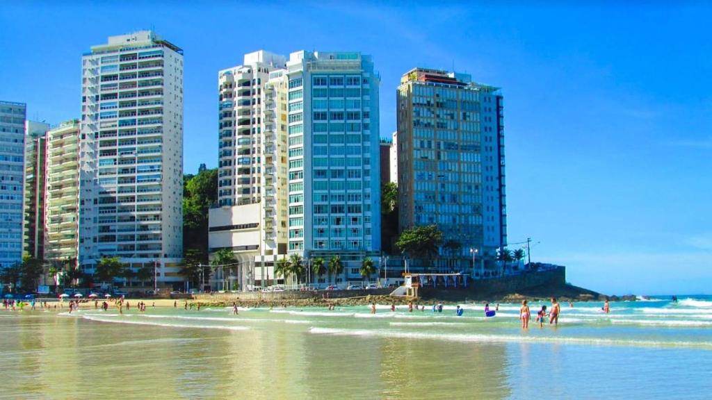 a beach with tall buildings and people in the water at Condominio Edificio Thaiti in Guarujá