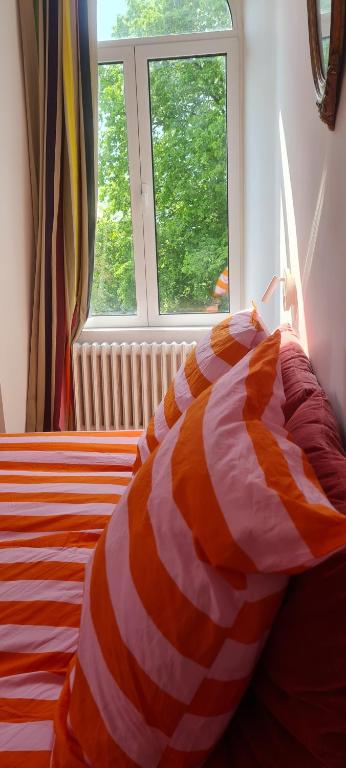 een bed met een oranje en wit gestreept dekbed in een slaapkamer bij Manoir du Haut Jussé in Vezin-le-Coquet