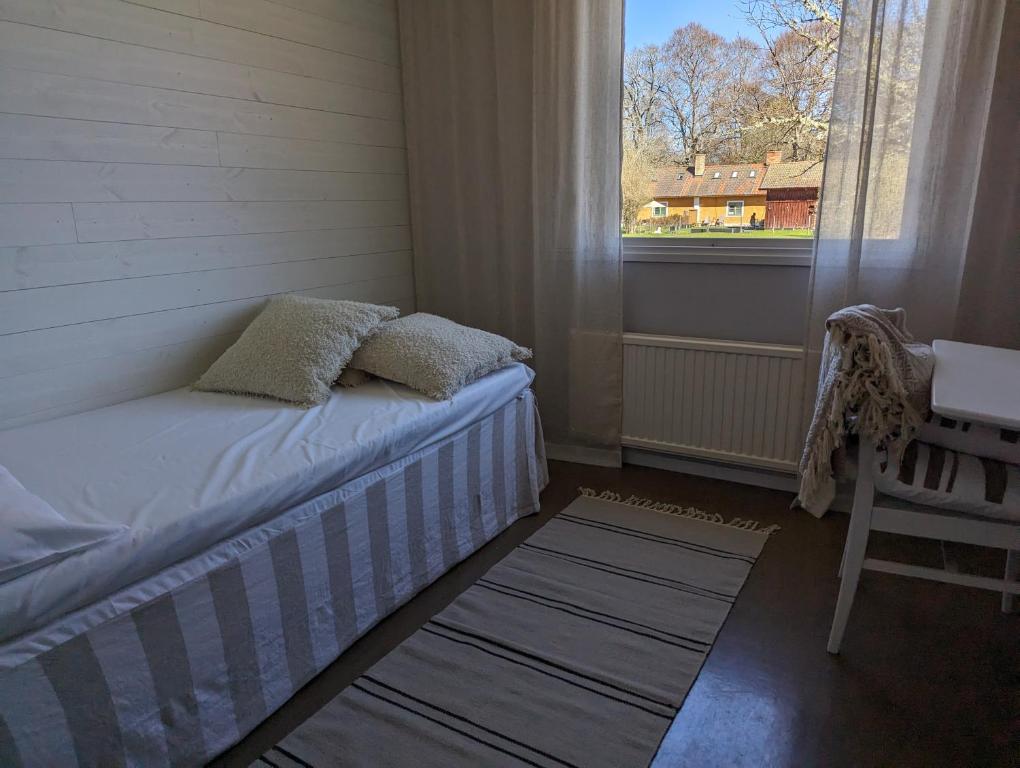 Habitación pequeña con cama y ventana en Värdshuset & Brukshotellet i Lövstabruk, en Lövstabruk