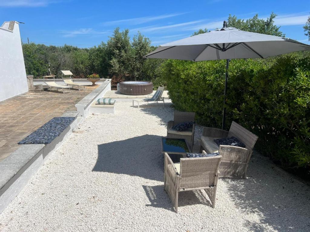 a patio with an umbrella and two chairs and an umbrella at Trullo La Quercia in Ostuni