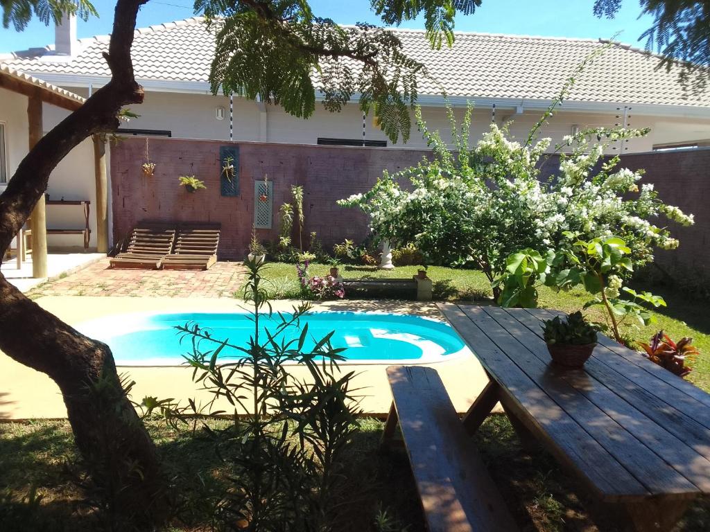 um quintal com uma piscina e uma mesa de madeira em Pousada Canto das Estrelas em Chapada dos Guimarães